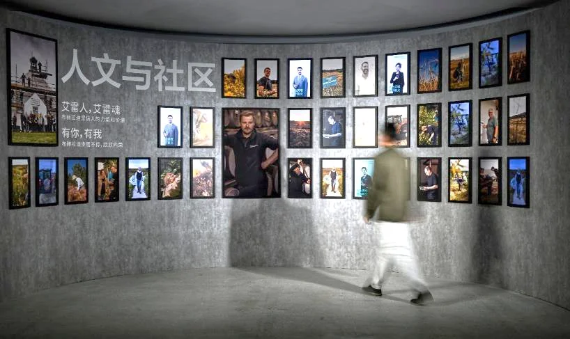 A person walking past a wall of pictures Description automatically generated