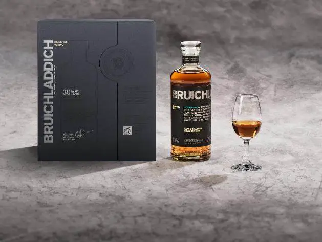 A bottle of alcohol next to a glass of liquor Description automatically generated