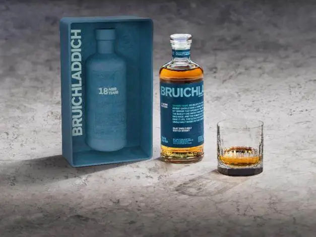 A bottle of alcohol next to a glass Description automatically generated